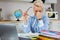 Tired stressed young teacher woman sitting at her desk with books in front laptop