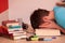 Tired student resting his head in his hands in the middle of a book