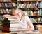 The tired student sleeps in library on pile books