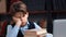 Tired teen schooler boy sleeping on desk laptop with stack of books learning homework at library