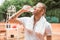 tired tennis player with towel drinking water after training