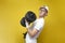 Tired thin guy nerd lifts heavy dumbbells and cries on a yellow background, a confused student in glasses is training