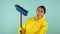 Tired and tired cleaning lady in a yellow suit on a blue background. The concept of professional house cleaning. A