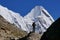 Tired tourist girl of Chinese etnicity with a sticks for walking on the background of the Himalayan mountains during trekking EBC