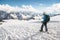 The tired traveler descends from the snowy top against the background of snow-capped mountains