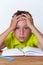 Tired tween boy sitting at the table with book