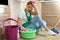 Tired woman with cleaning products sitting
