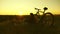 Tired woman cyclist resting in evening on edge of cliff and admiring sun. Free girl travels with bicycle at sunset