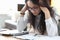 Tired woman with glasses sit at table and massages her head with her hands and think.