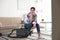 Tired woman sitting on vacuum cleaner