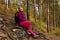 Tired woman traveler sat down to rest on a stone and looking up