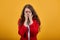 Tired woman in white shirt and red jacket covering nose with hands, crying