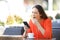 Tired woman yawning holding phone in a bar