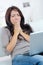 Tired woman yawns with laptop on sofa at home