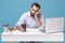 Tired young man in light shirt sit work at desk with pc laptop isolated on blue background. Achievement business career