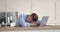 Tired young man sleeping on laptop at workplace
