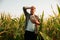 Tired young man stand in cornfield, took off hat, wipe sweat from forehead, front view, looking away.