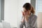 Tired young woman massaging nose bridge at workplace