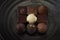 Title: A pile of exquisitely beautiful chocolate cubes placed on a dark grey ceramic plate with a water ripple.
