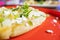 Tlacoyo with cheese, green sauce, and sour cream on a red plate