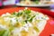 Tlacoyo with cheese, green sauce, and sour cream on a red plate