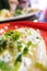 Tlacoyo with cheese, green sauce, and sour cream on a red plate