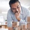 To create success youve got to envision it. a young businessman working with wooden building blocks in a modern office.