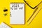 To do list 2023. Notepad and mobile phone on a yellow background.