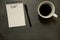 To do list on gridded spiral notepad with cup of coffee, on slate table top - from above, minimal