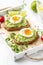 Toast with avocado puree and soft-boiled egg on white tray, liquid yolk, delicious breakfast, light sandwich. Healthy food