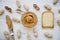 Toast, bowl of peanut butter, knife and peanuts in shells on a white wooden background, top view.