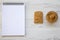 Toast, bowl of peanut butter and notebook on a white wooden background, top view.