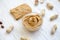 Toast, bowl of peanut butter and peanuts in shells on a white wooden background,