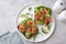 Toast with dark rye bread, avocado, smoked salmon and cucumber on white plate