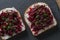 Toast from a slice of bread with white cream cheese, stewed beetroot pulp, seeds and green dill on wooden board. Delicious