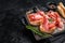 Toast with tomatoes and cured Slices of jamon serrano ham, prosciutto crudo parma on wooden board with rosemary. Black