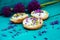 Toasted bread bruschetta with cream cheese and garlic edible flowers on olive wooden cutting board on stone slate gray background.