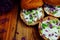 Toasted bread bruschetta with cream cheese and garlic edible flowers on olive wooden cutting board on stone slate gray background.