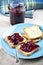 Toasted cereal bread slices on blue ceramic plate and homemade wild berries jam in jar, spoon and linen napkin closeup on rustic