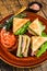 Toasted Club sandwiches with pork ham, cheese, tomatoes and lettuce on a plate. wooden background. Top view