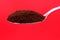 Toasted coffee spoon closeup isolated in red background.