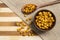 Toasted corn with mustard and honey inside brown ceramic and wooden spoon on bamboo wooden background