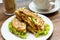 Toasted filled bagel with salad on a white plate.