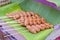 Toasted meatballs on a wooden stick placed on banana leaves