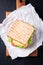 Toasted sandwich with salad leaves, tomatoes and cheese with fork on a cutting board on a dark background