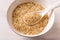 Toasted sesame seeds and white spoon in a porcelain bowl. Roasted organic benne grains closeup. White til as asian cuisine