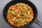 Toasted vegetables with minced meat in a cast iron pan, gray background, close up. stew, hearty healthy lunch