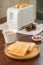 Toaster with sandwiches and jam on a light kitchen table.