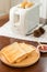 Toaster with sandwiches and jam on a light kitchen table.