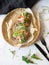 Toasts with avocado slices, prosciutto, arugula and onion on wicker tray on marble table.